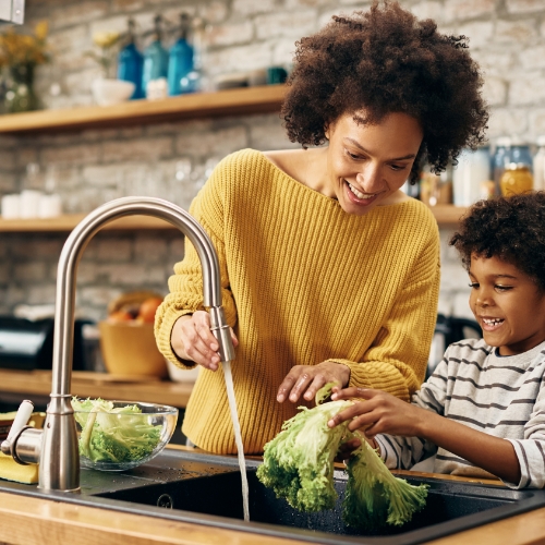 Mother and Son Washing Vegetables in Kitchen Sink