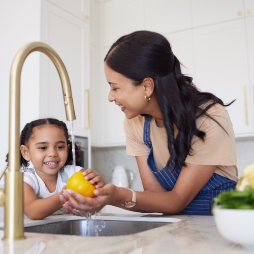 Mother and Son Washing Vegetables in Kitchen Sink